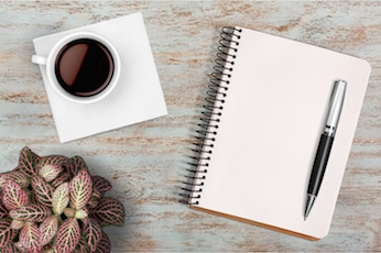 Image of a pen and notebook with a cup of coffee