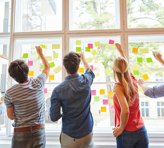 Image of people placing post-it notes on a window together