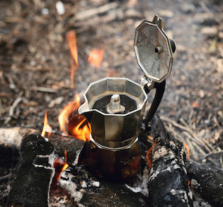 Image of coffee bubbling in a vintage kettle over a fire