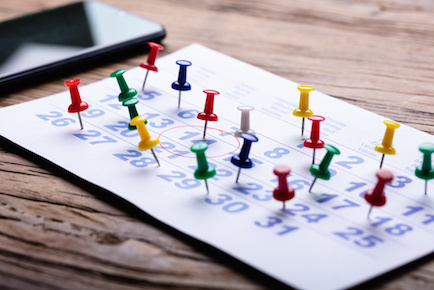 Calendar overcrowded with push pins for too many commitments