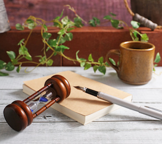 Image of an hourglass, a journal, and a pen