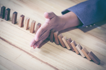 Image of Hand Stopping Dominoes