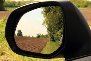 Image of rear-view mirror looking at a plowed field