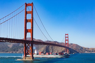 Image of a freight ship passing below the Golden Gate Bridge in San Francisco, California