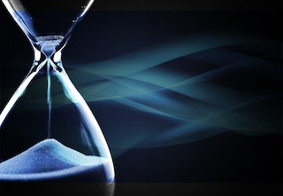 Image of an hourglass nearly out of time against dark blue background