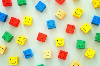 image of different emotions drawn on colorful cubes, wooden background.