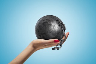 Image of woman's hand holding a ball with a short length of chain against a sky-blue background