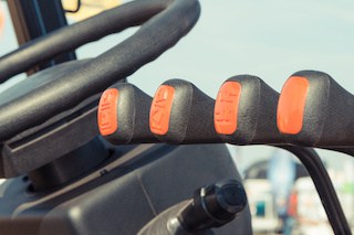 image of operating control panel with four levers and steering wheel in agricultural or industrial forklift-type machine