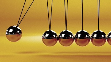 Image of orange and black metal Newton's cradle on a sunset-orange background