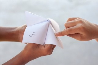Image of children's hands playing a paper fortune-teller game